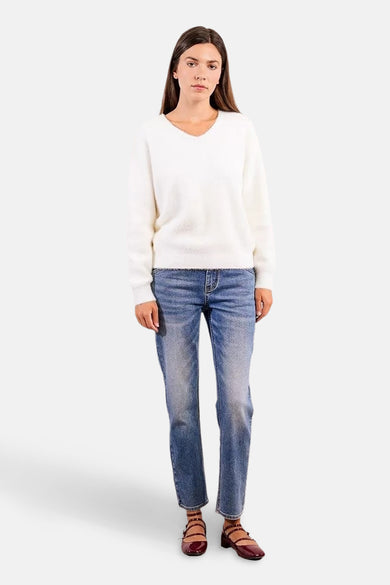 Witte V-hals trui van Molly Bracken, gedragen met lichtblauwe jeans en bordeauxrode nette schoenen.