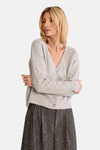 Soft gray cardigan with scalloped V-neck and button front, worn over a dark textured skirt, side view.