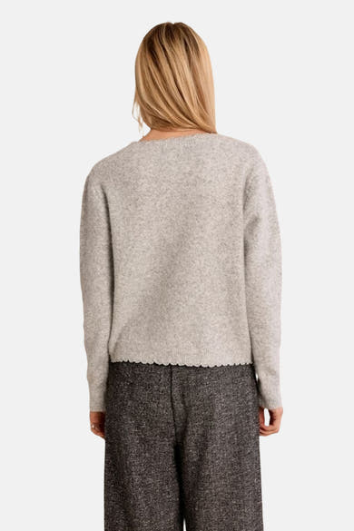 Grey marled cardigan with scalloped hem, back view, worn with dark textured trousers