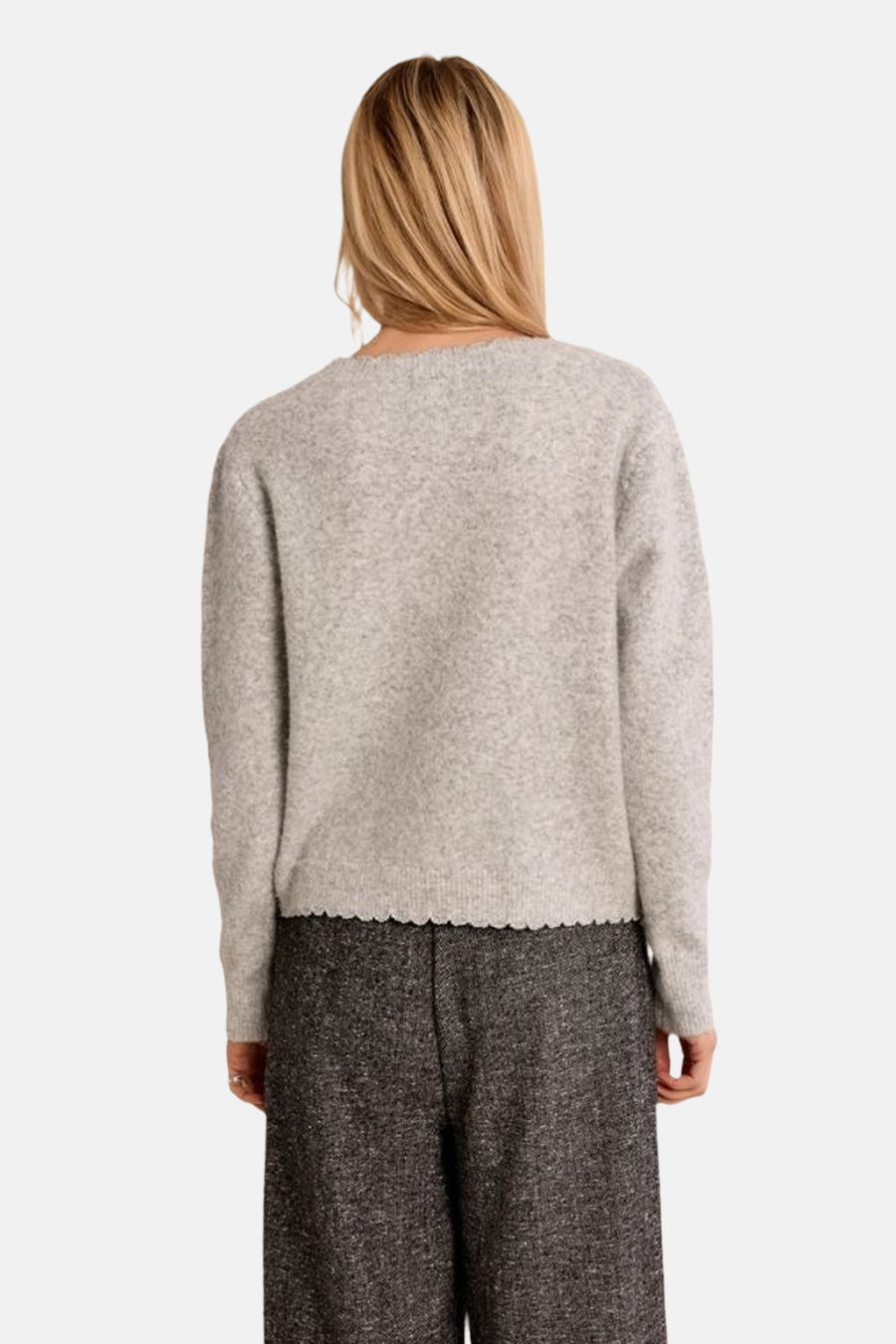 Grey marled cardigan with scalloped hem, back view, worn with dark textured trousers