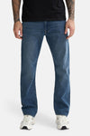 Mid blue denim jeans by LEWIS, straight-leg fit with faded wash, front view on model wearing black top and white sneakers