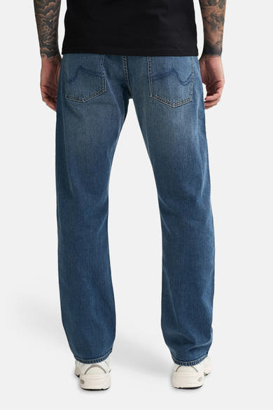 Mid blue denim jeans by LEWIS, back view, relaxed fit with classic stitching and white sneakers.