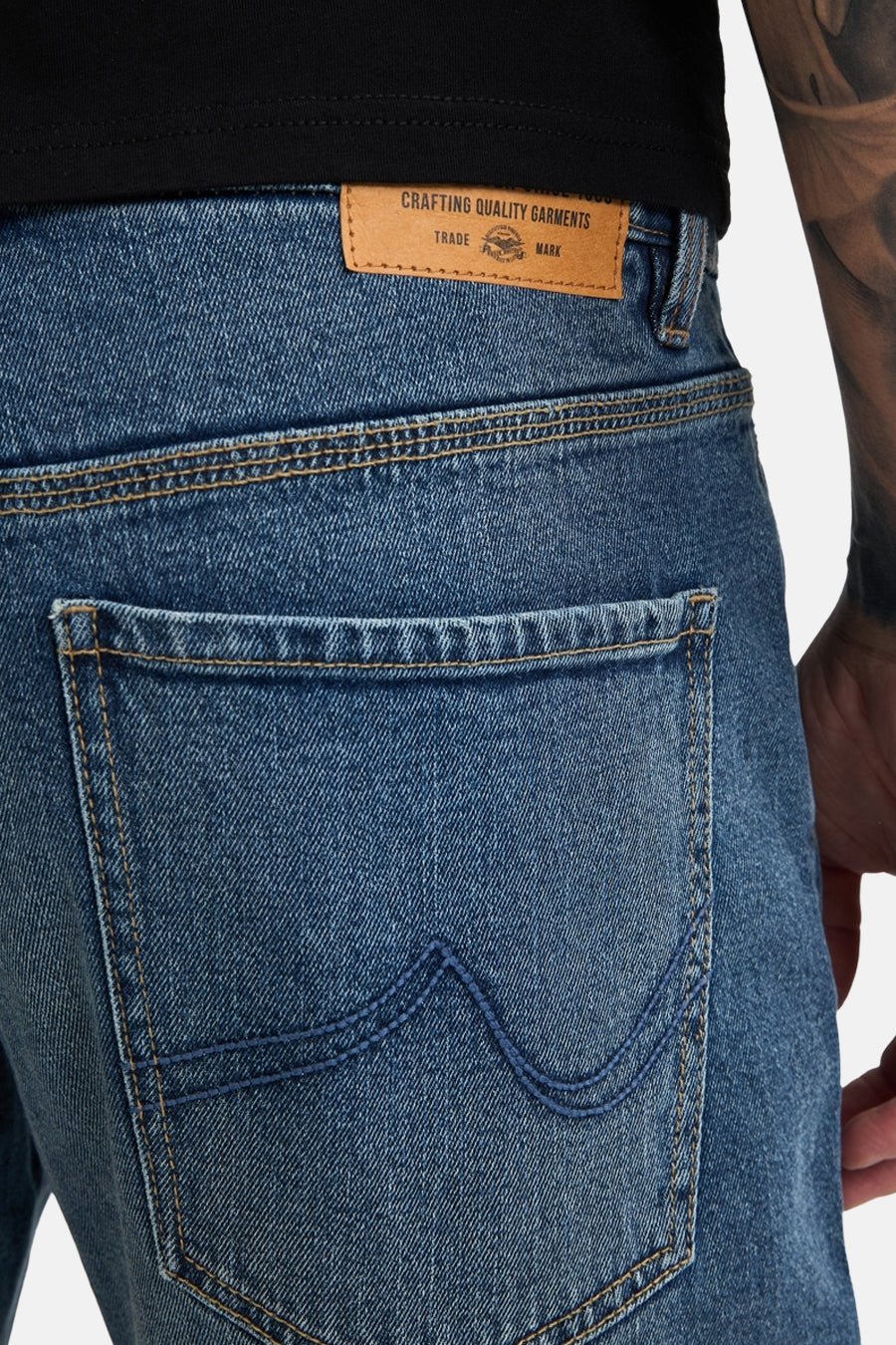 Mid blue denim jeans by Lewis, back view with tan leather waistband label and contrast stitching on rear pocket