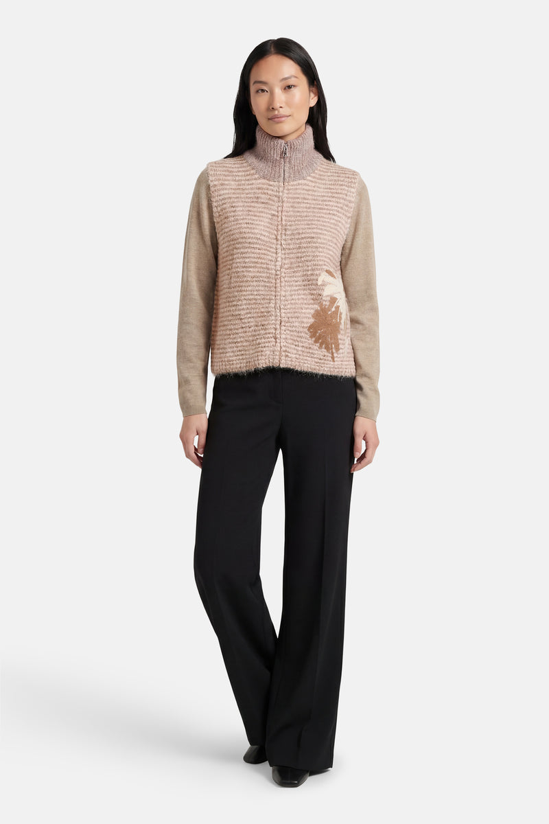 Beige ADORE cardigan met horizontale strepen, met aangebracht bloemenpatroon en wijde zwarte broek.