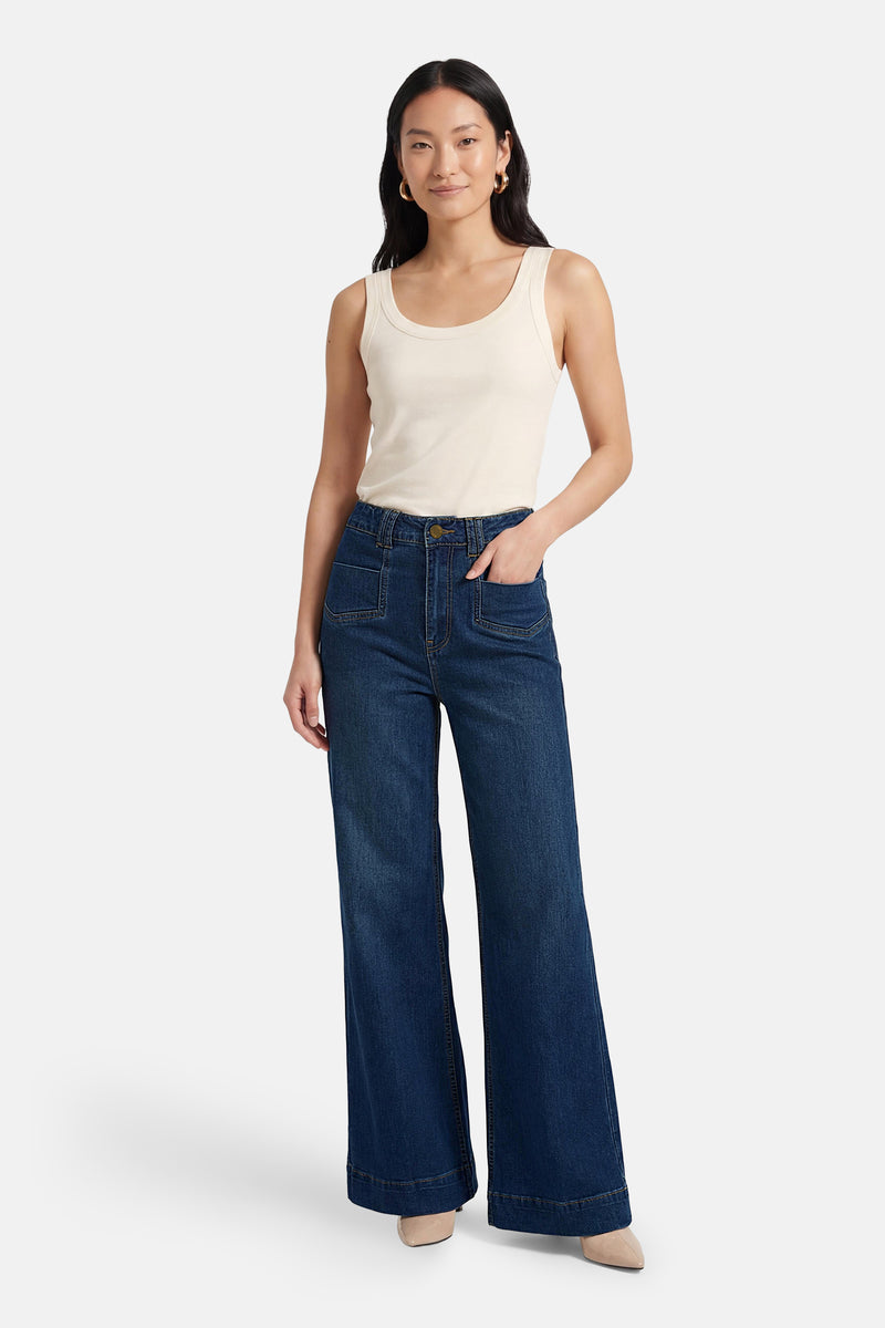 Jean large en denim bleu moyen d'ADORE, porté avec un débardeur crème et des escarpins vernis.
