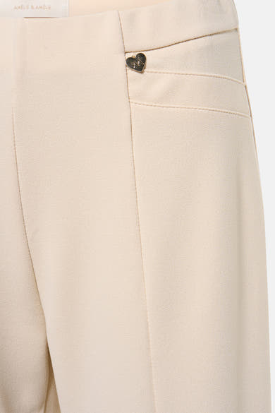 Pantalon beige par AMELIE ET AMELIE avec poche passepoilée et détail décoratif en forme de cœur.
