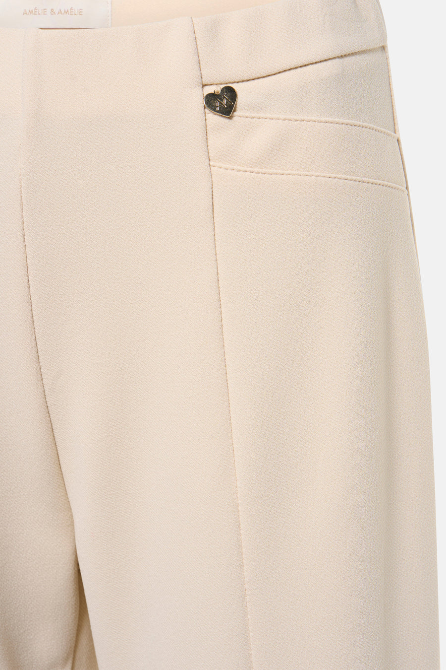 Pantalon beige par AMELIE ET AMELIE avec poche passepoilée et détail décoratif en forme de cœur.
