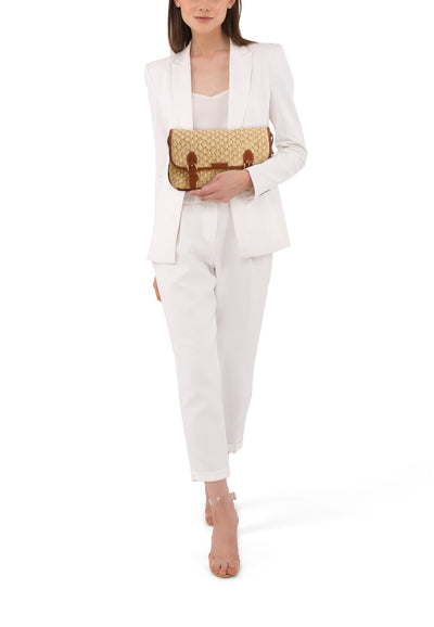 Cognac leather-trimmed woven handbag with double buckle closure, worn by model in white suit and clear heels, front view