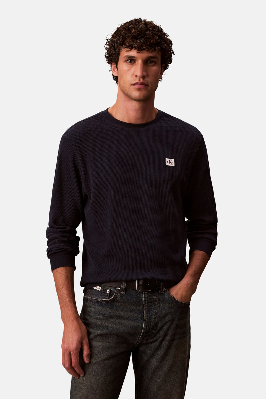 Blauwe T-shirt met lange mouwen van Calvin Klein, wafelpatroon, gedragen met een donkere spijkerbroek en een zwarte riem.