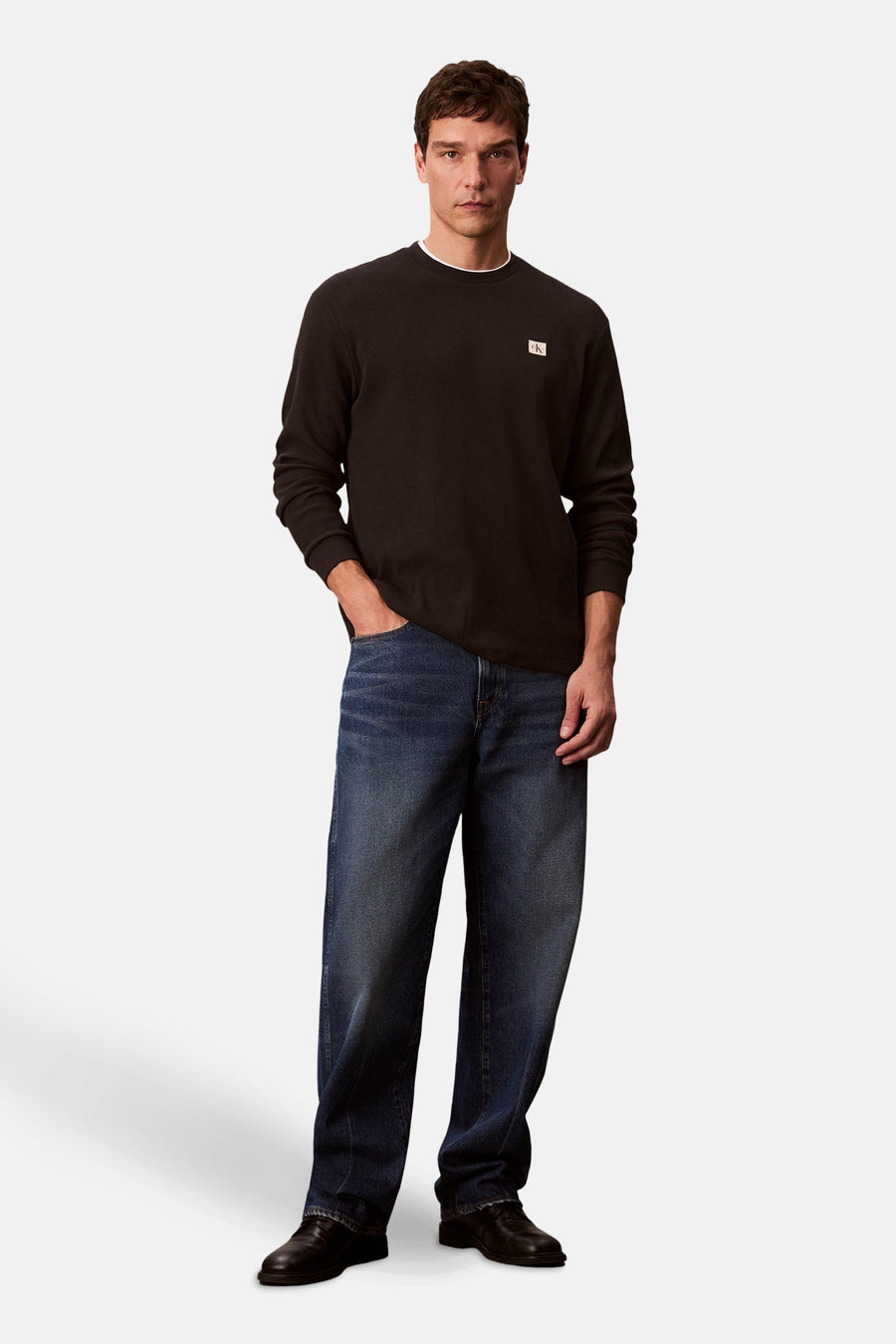 Zwart T-shirt met lange mouwen van Calvin Klein, gedragen met een wijde spijkerbroek en leren schoenen.