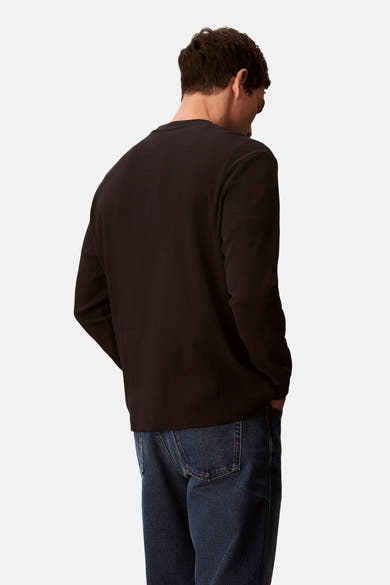 Zwart T-shirt met lange mouwen van Calvin Klein, van achteren gezien, gedragen met een spijkerbroek.