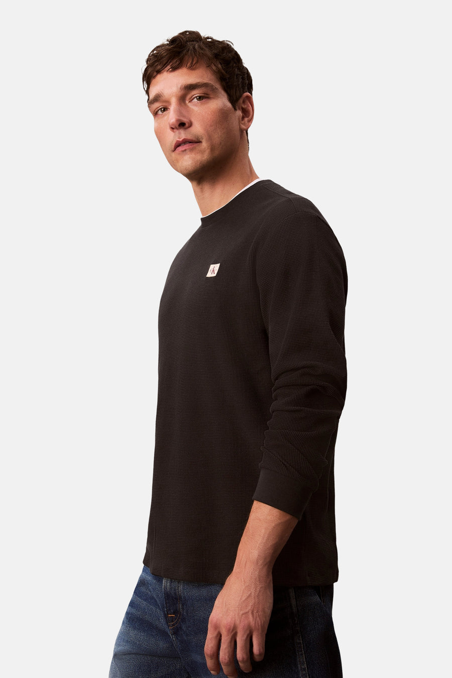 Zwart T-shirt met lange mouwen van Calvin Klein, wafelstructuur, gedragen met een blauwe jeans.