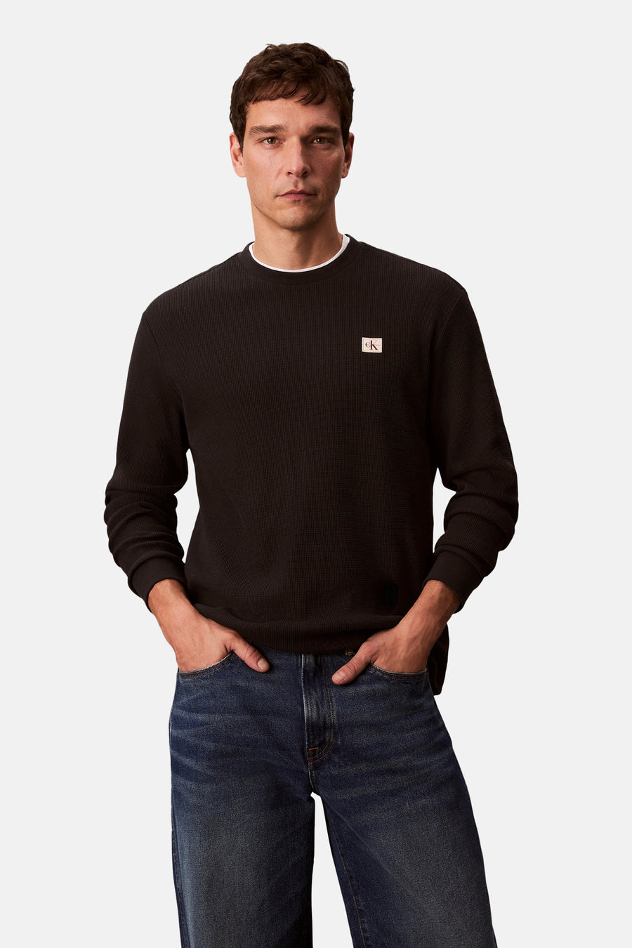 Zwart T-shirt met lange mouwen van Calvin Klein, wafelstructuur, gedragen met een blauwe jeans.