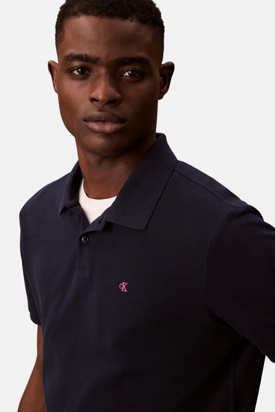 Polo bleu marine en maille piquée de Calvin Klein avec logo brodé rose.