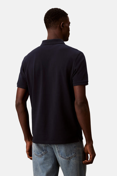 Marineblauwe Calvin Klein polo, achterkant, gedragen met een lichtblauwe casual spijkerbroek.