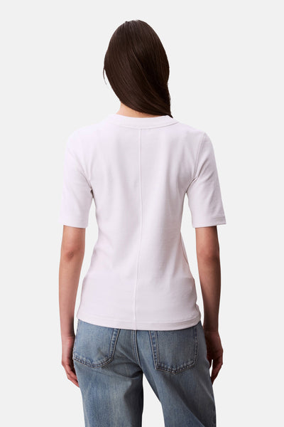 T-shirt blanc à manches courtes de Calvin Klein, avec une couture verticale au milieu du dos, porté avec un jean bleu.
