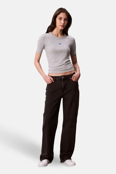 T-shirt gris à manches courtes de Calvin Klein, porté avec un jean noir ample et des chaussures de sport blanches.