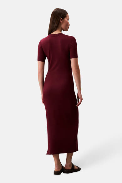 Robe longue bordeaux de Calvin Klein, coupe ajustée, texture côtelée, portée avec des sandales noires, vue de dos.
