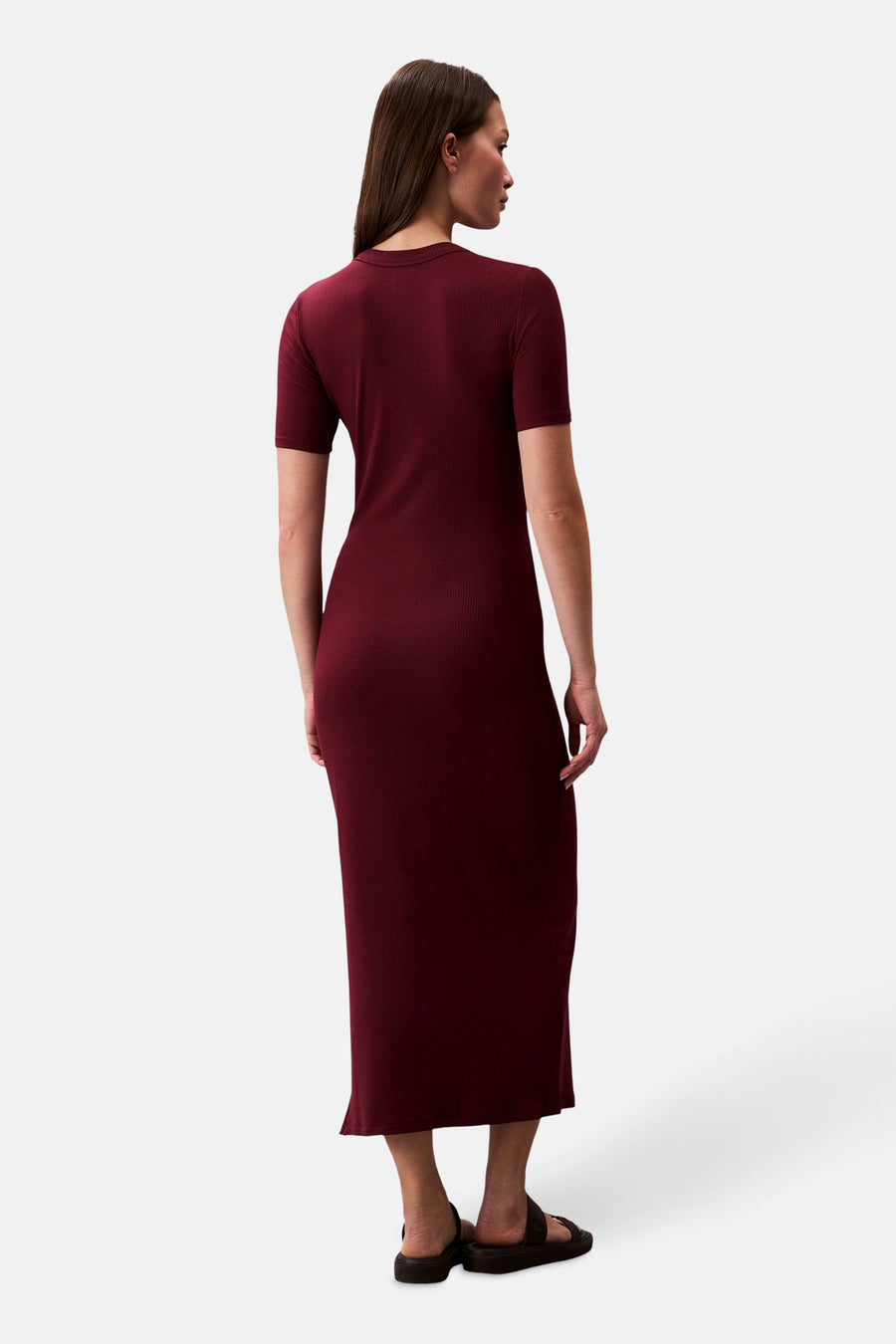 Robe longue bordeaux de Calvin Klein, coupe ajustée, texture côtelée, portée avec des sandales noires, vue de dos.