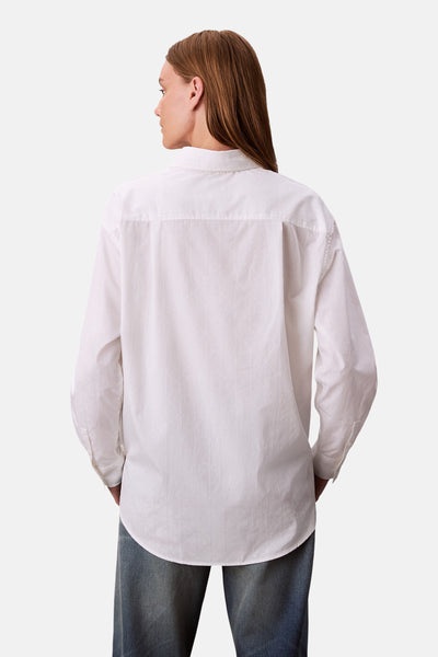 Chemise blanche à manches longues de Calvin Klein, avec un motif subtil, portée avec un jean bleu, vue de dos.
