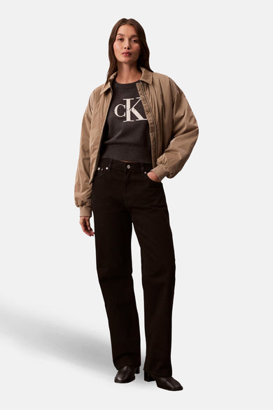 Pull à col rond gris de Calvin Klein, avec logo blanc, porté avec une veste et un pantalon noirs.
