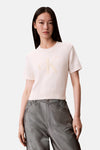 Pull écru à col rond de Calvin Klein, avec le logo ton sur ton sur le devant, porté avec un pantalon gris.