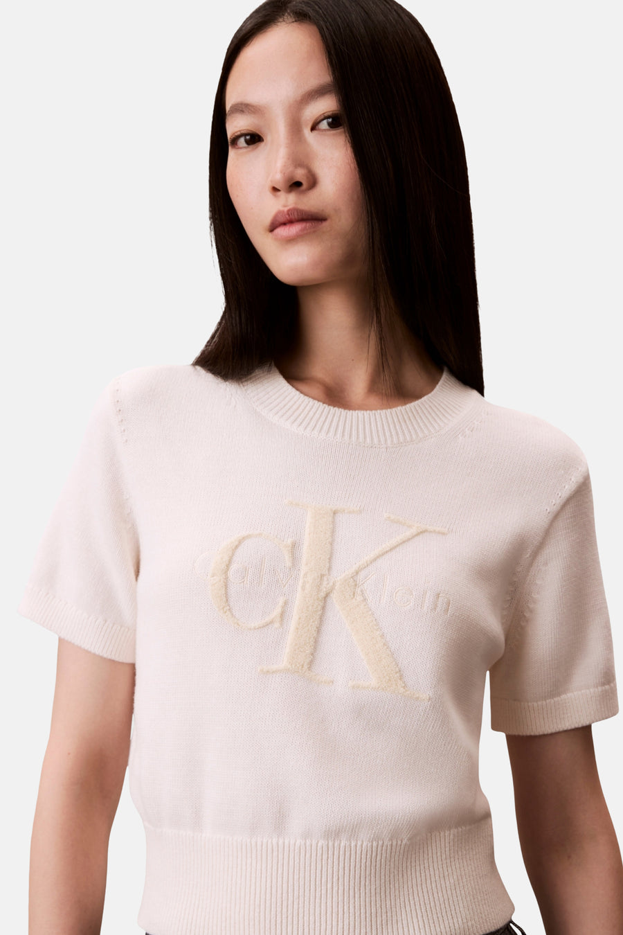 Pull écru à col rond de Calvin Klein, avec le logo en relief sur le devant.

