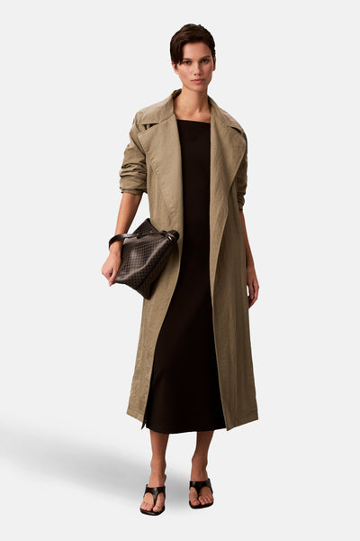Zwarte Calvin Klein jurk, gedragen met een kaki trenchcoat en sandalen met hak.