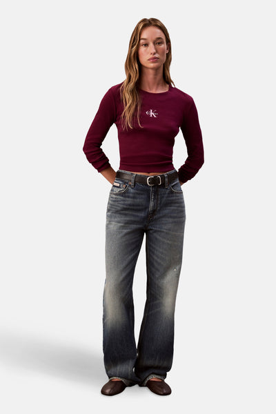 T-shirt bordeaux à manches longues de Calvin Klein, porté avec un jean taille haute et une ceinture noire.
