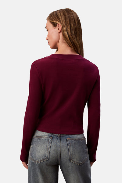 Bordeaux T-shirt met lange mouwen van Calvin Klein, in ribgebreide stof, gedragen met een low-rise jeans.