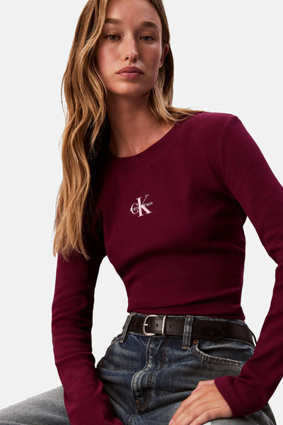 Bordeaux T-shirt met lange mouwen van Calvin Klein, in ribgebreid materiaal, gedragen met een spijkerbroek en een riem.