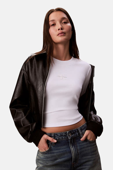 Wit T-shirt met lange mouwen van Calvin Klein, gedragen met een zwart leren jack en een blauwe spijkerbroek.