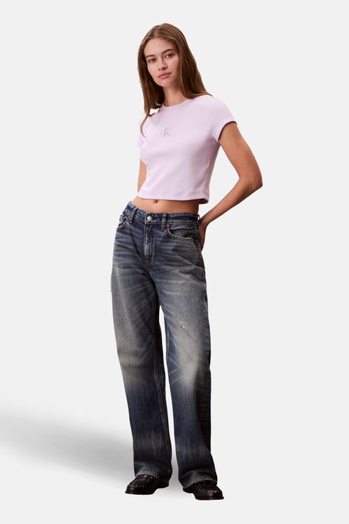 T-shirt violet à manches courtes de Calvin Klein, porté avec un jean ample délavé et des mocassins noirs.
