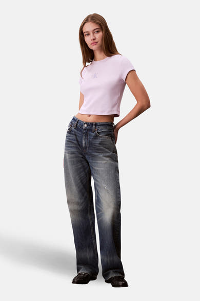 Paars T-shirt met korte mouwen van Calvin Klein, gedragen met een wijde, uitgewassen spijkerbroek en zwarte loafers.