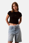 Zwart T-shirt met korte mouwen van Calvin Klein, gedragen met een high-waisted jeans en een zichtbaar wit slipje.