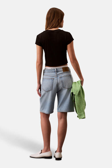 Zwart T-shirt met korte mouwen van Calvin Klein, gedragen met een blauwe spijkerbroek en witte loafers.