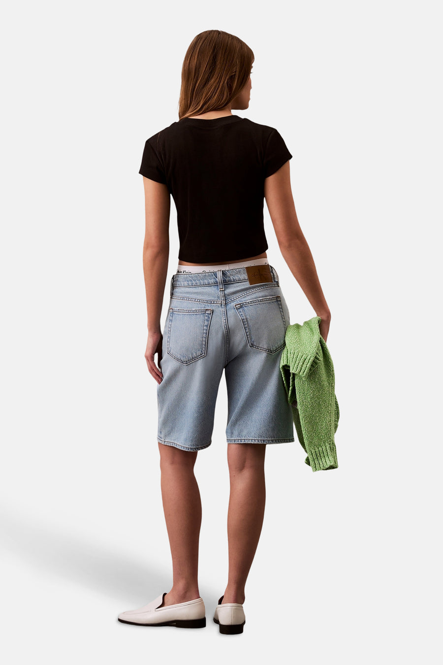 Zwart T-shirt met korte mouwen van Calvin Klein, gedragen met een blauwe spijkerbroek en witte loafers.