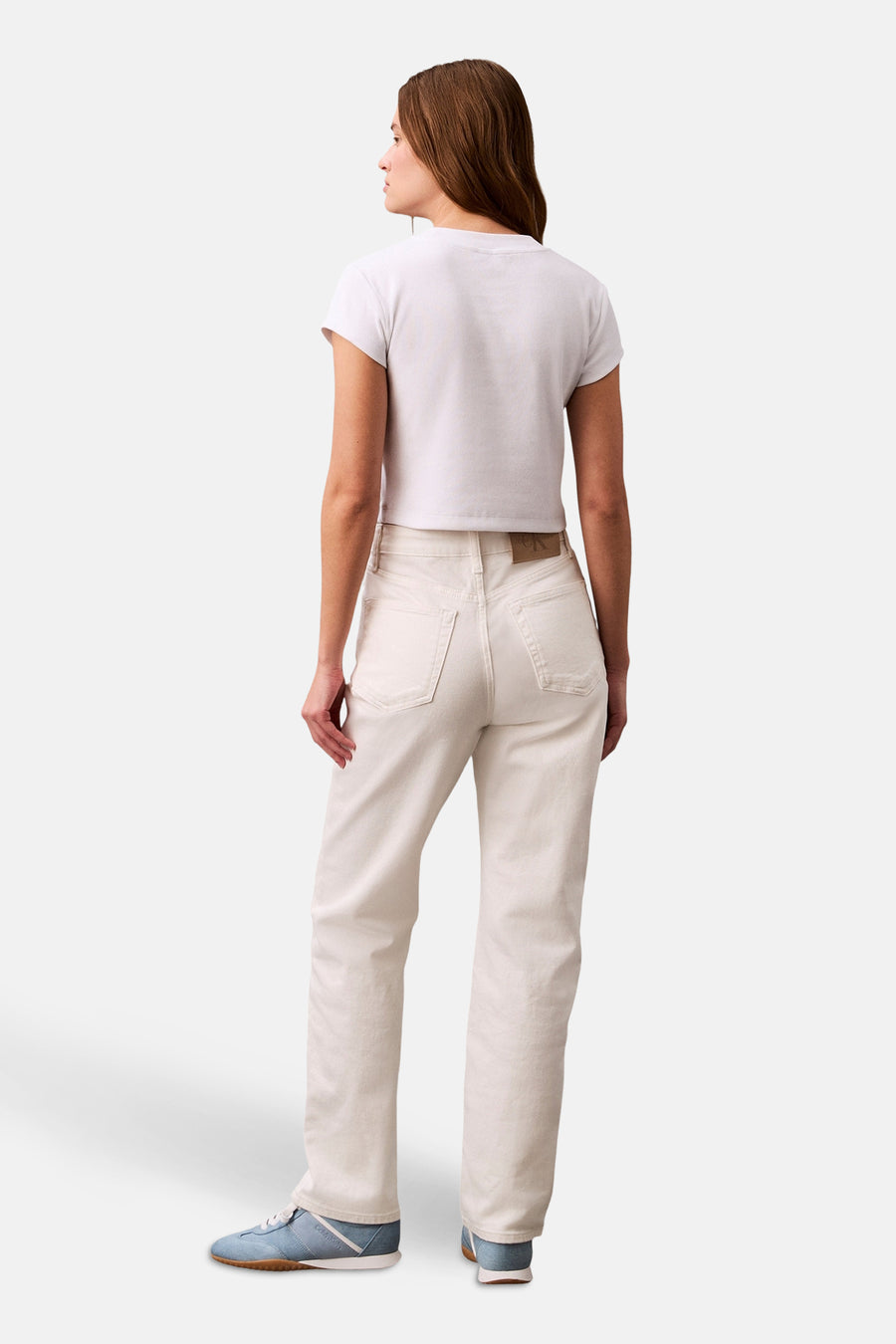 Wit T-shirt met korte mouwen van Calvin Klein, gedragen met een high-waisted jeans en blauwe sneakers.
