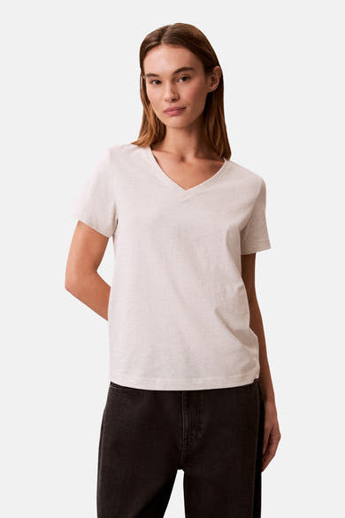 Beige T-shirt met korte mouwen van Calvin Klein, gedragen met een zwarte high-waist jeans.