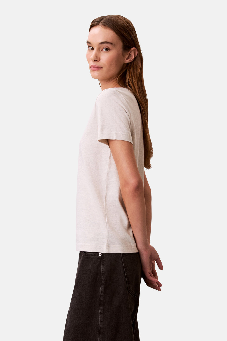 Beige T-shirt met korte mouwen van Calvin Klein, gedragen met een donkere broek, van opzij gezien.
