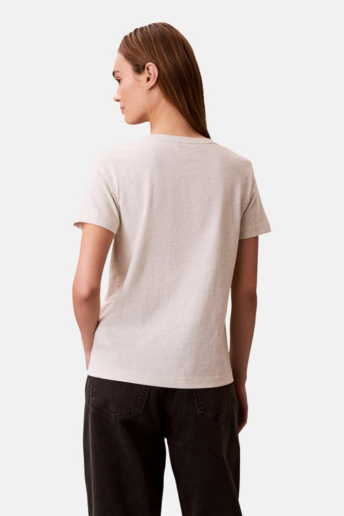 T-shirt à manches courtes beige de Calvin Klein, vu de dos, porté avec un pantalon foncé.
