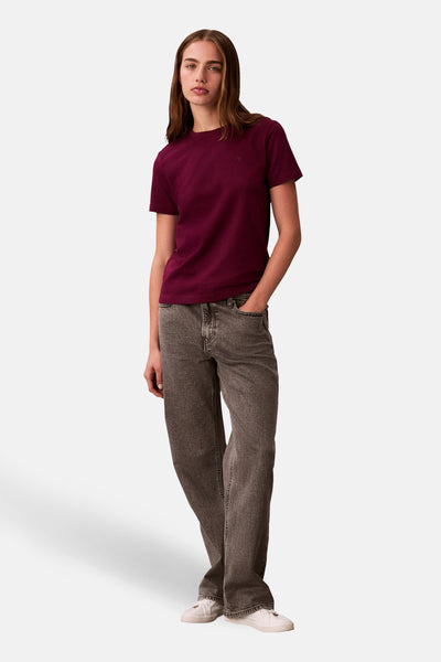 T-shirt rouge à manches courtes de Calvin Klein, porté avec un jean gris et des baskets blanches.