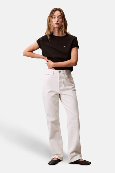 Zwart T-shirt met korte mouwen van Calvin Klein, gedragen met een witte high-waist jeans en zwarte platte schoenen.