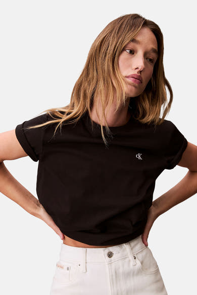 Zwart T-shirt met korte mouwen van Calvin Klein, gedragen met een hoge taille broek in gebroken wit.