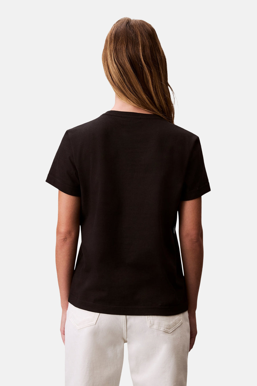 Zwart T-shirt met korte mouwen van Calvin Klein, gedragen met een witte broek, achtergezicht.