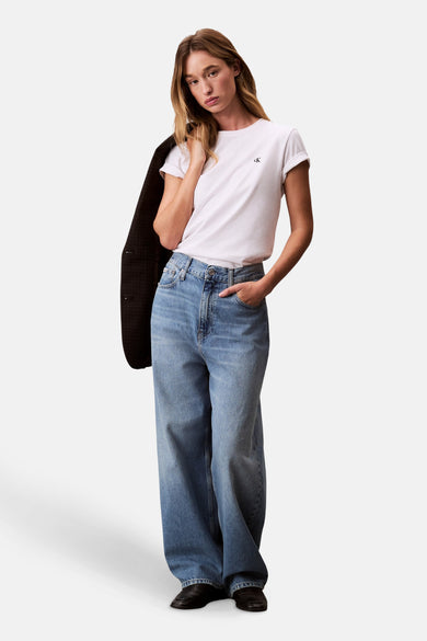 Wit T-shirt met korte mouwen van Calvin Klein, gedragen met een blazer en een wijde jeans.