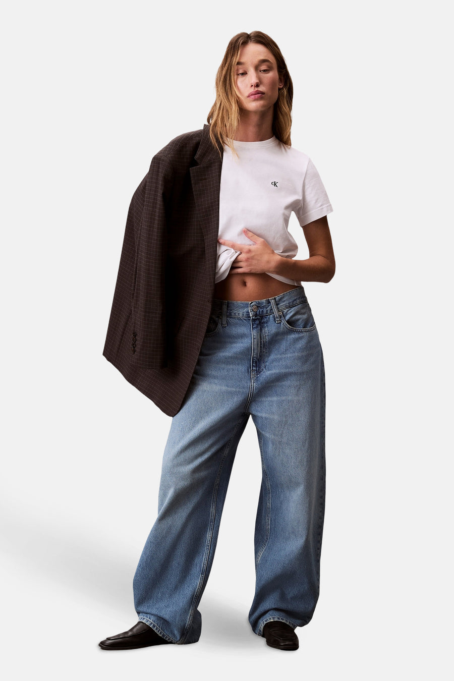 Wit T-shirt met korte mouwen van Calvin Klein, gedragen met een bruin geruit colbert en een wijde blauwe spijkerbroek.