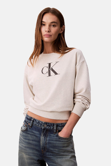Beige rondehals sweatshirt van Calvin Klein, gedragen met een blauwe low-rise jeans.