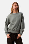 Sweat vert en coton de Calvin Klein, porté avec un t-shirt blanc et un jean noir.