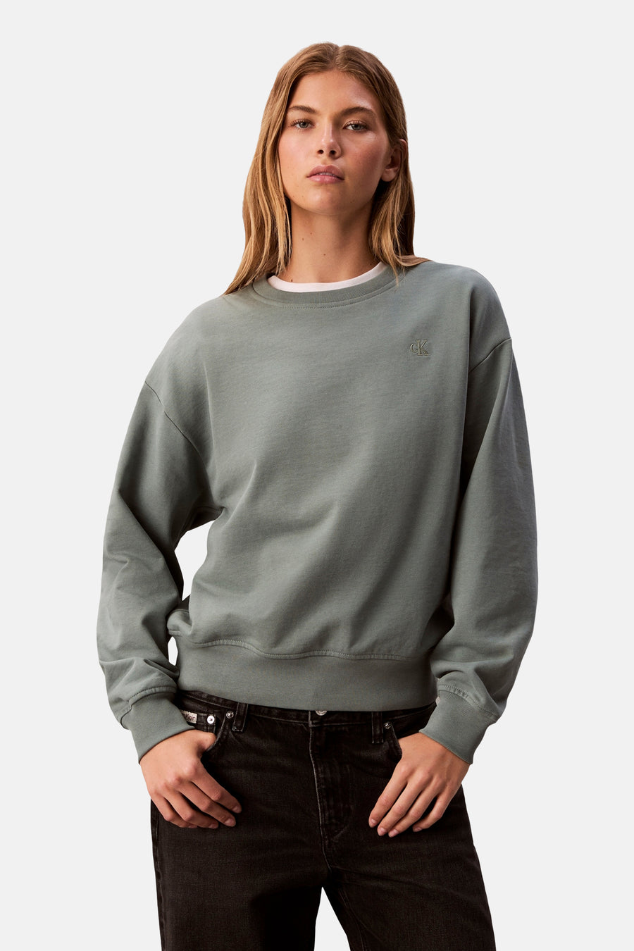 Sweat vert en coton de Calvin Klein, porté avec un t-shirt blanc et un jean noir.